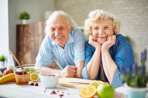 Zwei Senioren lehnen lächelnd auf dem Küchentresen