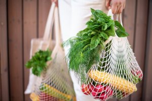 Frau trägt Gemüseeinkauf in Einkausnetzen