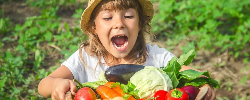 Mädchen hält einen Korb mit frischem Gemüse