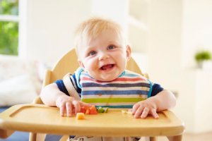 Kleinkind sitzt lachend im Kinderstuhl