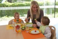 Kleinkinder essen mit Erzieherin Rohkost