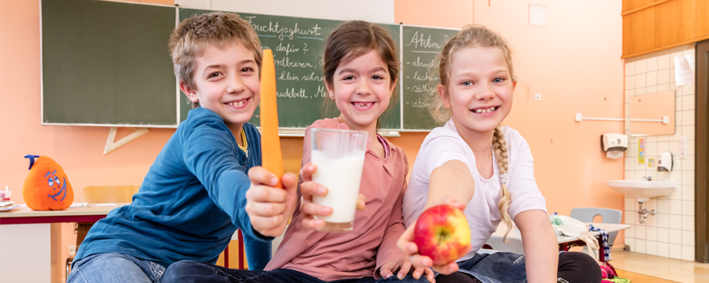 Schulkinder mit Obst, Gemüse und Milch in den Händen