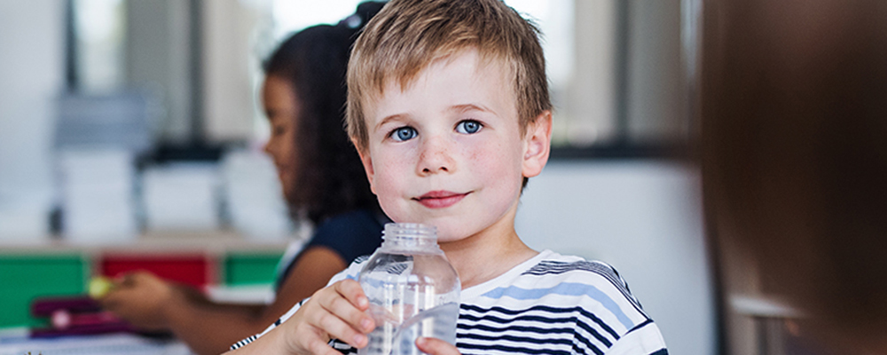 Junge trinkt Wasser in Klassenzimmer