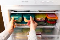 Kühlschrank wird mit Lebensmitteln in Frischhaltedosen eingeräumt