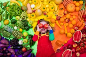 Gemüse in Regenbogenfarben und ein Kind