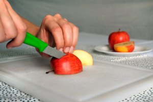 ein Apfel wird auf einem Brett geschnitten