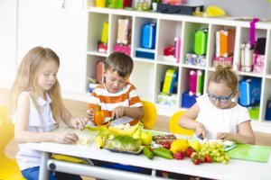 Kindergartenkinder schneiden Obst und Gemüse