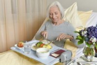 Seniorin isst im Krankenhausbett
