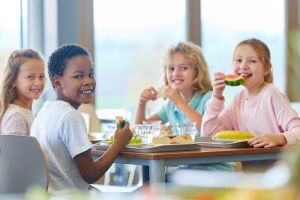 4 Schulkinder essen fröhlich in der Schulmensa