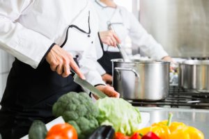 Koch schneidet Gemüse in einer Küche der Gemeinschaftsverpflegung