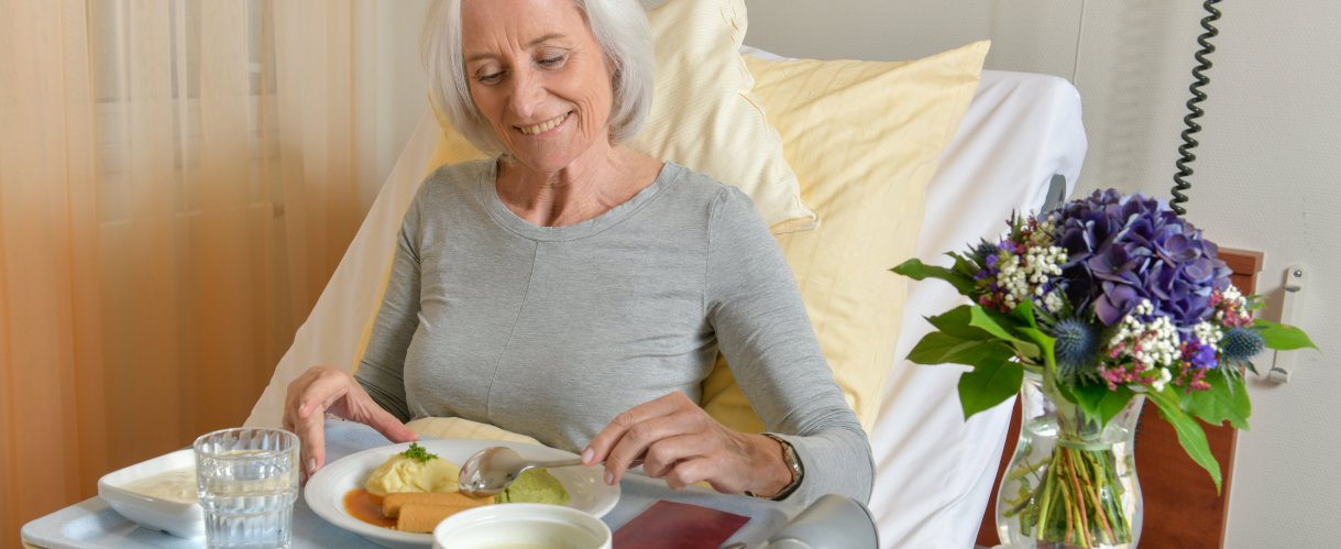 Patientin einer Klinik isst zufrieden ihre Verpflegung