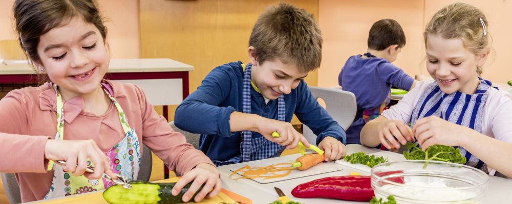 Grundschulkinder schälen im Klassenzimmer Gemüse