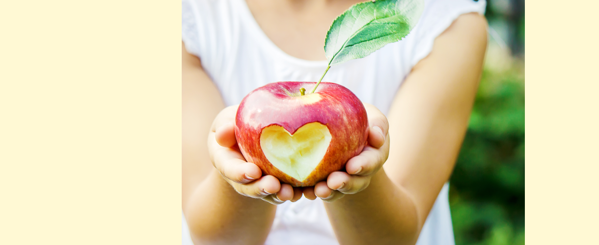 Kind hält einen Apfel mit einem eingeschnitzten Herz